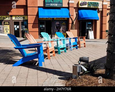 Sedie a sdraio Adirondack colorate vuote allineate al villaggio di Harborwalk a Destin, Florida, USA. Foto Stock