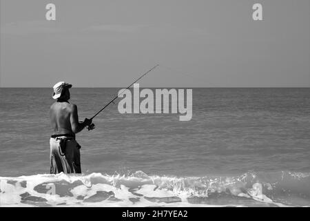 Uomo con cappello pesca in oceano Foto Stock