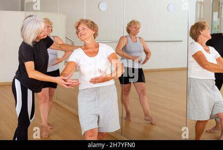 Le donne anziane che esercitano la danza balletto si muove con il formatore Foto Stock