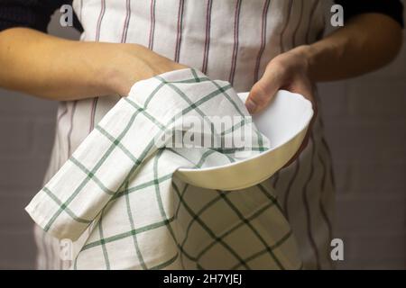 Un giovane pulisce un piatto con un panno di cotone Foto Stock