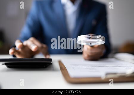 Indagine sulle frodi aziendali. Auditor che usa la lente di ingrandimento per indagare Foto Stock