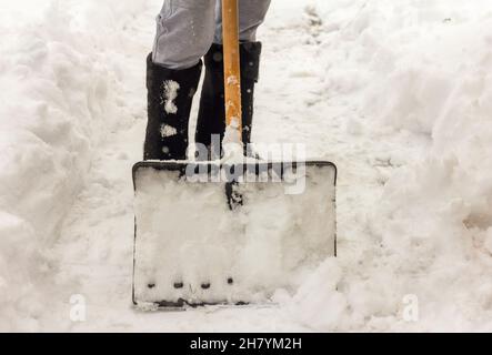 Un uomo pulisce i sentieri nel cortile dalla neve Foto Stock