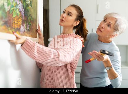 Madre e figlia che mettono l'immagine sul muro Foto Stock