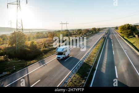 Camper auto da diporto con alcove guida lungo la campagna rurale autostrada. Vacanze e viaggi in motor home. Foto Stock