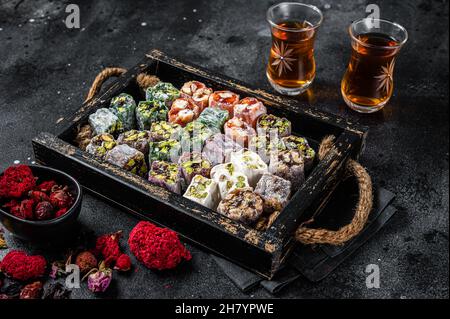Turco Delight Lukum, dolci orientali con noci e tè nero. Sfondo nero. Vista dall'alto Foto Stock