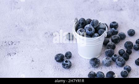 Mirtilli congelati in secchio su fondo di cemento. Frutta di stagione biologica sana sfondo. Cibo biologico. Raccogliendo, preparando cibo per Foto Stock