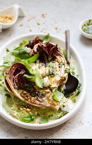 Insalata di radicchio arrosto con feta, tahini verdi, pinoli e pesto di basilico. Radicchio rosso di treviso tardivo, cicoria rossa italiana. Pasto sano reci Foto Stock