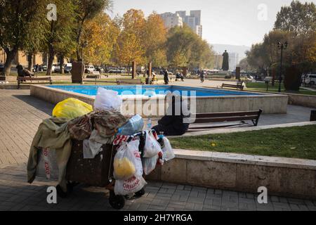 Jerewan, Armenia. 14 novembre 2021. Un uomo anziano si siede accanto ad un carro con i suoi effetti personali in un parco del centro. Credit: Christian Charisius/dpa/Alamy Live News Foto Stock