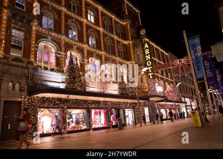 Dublino, Irlanda - 24 novembre 2021: Gli acquirenti passano le luci e le decorazioni natalizie presso il grande magazzino Arnotts di Henry Street, The Foto Stock