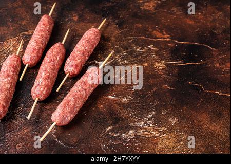 Kebab di carne crudo kofta salsicce su spiedini. Sfondo scuro. Vista dall'alto. Spazio di copia Foto Stock