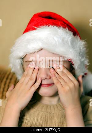 Sad Little Girl in cappello di Babbo Natale a casa Foto Stock