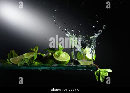 Cocktail mojito con fette di lime e menta. Una fetta di lime cade nel vetro creando un bel tuffo. Foto Stock