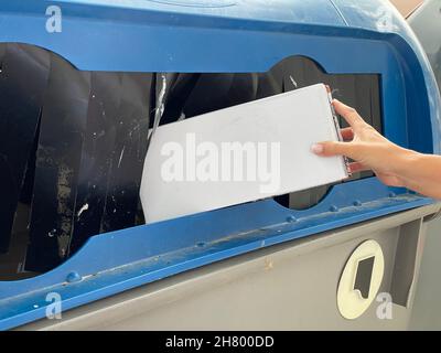 le mani di una donna che getta la carta in un cestino - concetto di sostenibilità Foto Stock