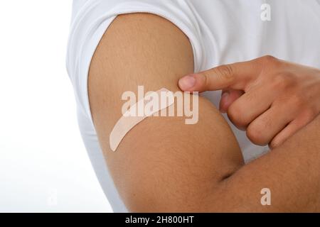Uomo che mostra il suo braccio con una banda-aiuto dopo aver ottenuto il vaccino contro il covid-19. Foto Stock