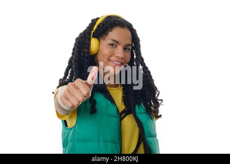 Donna sorridente che mostra il pollice mentre ascolta la musica con le cuffie. Foto Stock