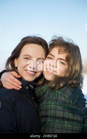 sorridente figlia adulta, di circa 17-18 anni, e madre di circa 40 anni, guarda la macchina fotografica, in posa per la foto di famiglia. intimo momento tenero della mamma a. Foto Stock