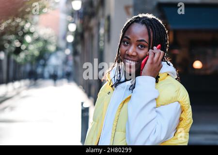 Donna che parla al telefono mentre si è in piedi all'aperto. Foto Stock