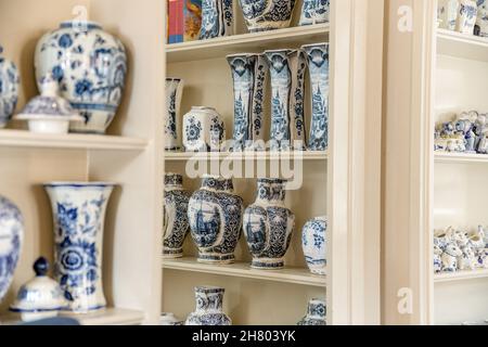 Collezione di vari vasi in ceramica con ornamento bianco e blu posti su mensole in camera luminosa su tavolo Foto Stock