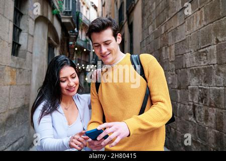Coppia utilizzando un telefono cellulare all'aperto sulla strada. Foto Stock