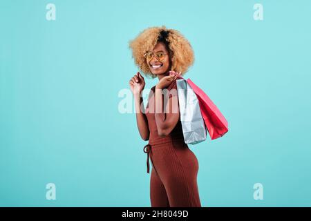 Donna afroamericana che tiene i sacchetti colorati di carta di shopping. Concetto di stagione delle vendite del Black Friday. Foto Stock