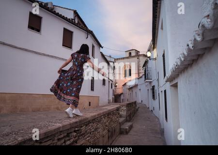 Vista posteriore del corpo del viaggiatore irriconoscibile in abito passeggiando su passerella lastricata in vecchie case a Setenil de las Bodegas Foto Stock