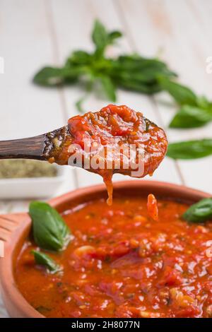 Da sopra di persona di raccolto che guida salsa di marinara in padella con cucchiaio di legno mentre cucinano in cucina Foto Stock