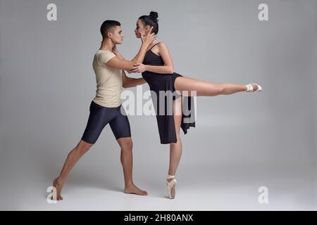 Due ballerini atletici moderni si posano su uno sfondo grigio dello studio. Foto Stock