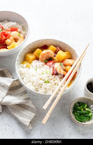 Gamberetti all'ananas in salsa dolce e aspre con riso bianco in una ciotola. Cucina thailandese Foto Stock