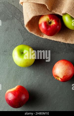 mele di diverse varietà sono viste su pietra scura e sfondo di legno. Ci sono mele da crostata verde e mele dolci rosse viste fianco a fianco. Concep Foto Stock