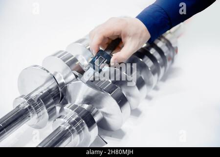 Il closeup engineer controlla le dimensioni con calibro a corsoio al dettaglio della finitura dopo la lavorazione della lamiera su macchina utensile cnc, controlla la qualità del prodotto prodotto Foto Stock