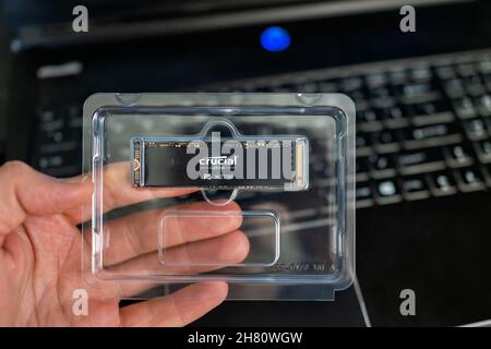 Banner Elk, USA - 23 giugno 2021: Macro primo piano di mano che tiene cruciale micro chip di micron e tastiera per computer portatile per sostituire il disco rigido morto Foto Stock