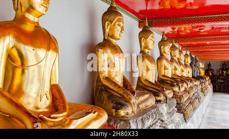 Fila di statue dorate del Buddha nel tempio buddista di Bangkok, Thailandia Foto Stock