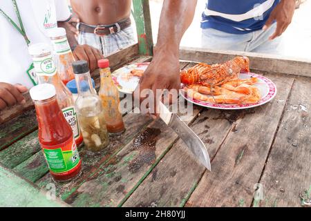 Cartagena de Indias, Colombia - 22 novembre 2010: Un uomo prepara dei frutti di mare da mangiare sulla spiaggia di Isla Baru, nei Caraibi colombiani Foto Stock