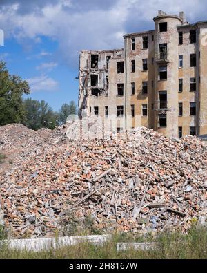 Un vecchio edificio prima della demolizione con un mucchio di macerie in primo piano riga Foto Stock