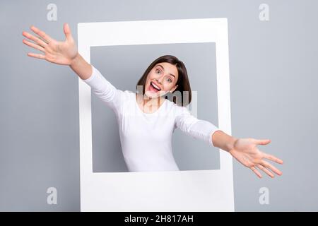 Foto di cute bruna giovane donna sembrano indossare camicia bianca isolato su sfondo grigio Foto Stock