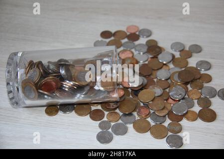 Caraffa con monete cadute su un tavolo di legno monete brasiliane denaro (Real / Reais). Sfondi e trame. Foto Stock