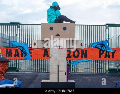 Dartford, Kent, UK 26 Novembre 2021 la ribellione di estinzione blocca tutti i tredici magazzini Amazon nel Regno Unito il Black Friday. La protesta mette in evidenza le loro pratiche commerciali sfruttative e distruttive dal punto di vista ambientale e il disprezzo per i diritti dei lavoratori in nome del profitto più lo spreco di Black Friday Credit: Denise Laura Baker/Alamy Live News Foto Stock