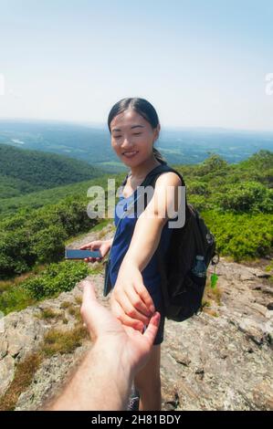 Una donna cinese sorridente felice che tiene una mano di mans in cima al monte alander a Washington, massachusetts in una giornata estiva soleggiata. Foto Stock