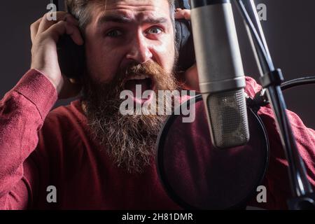 Cantante canto rock. Produttore di suoni che registra il brano in uno studio musicale. Karaoke entusiasta. Foto Stock