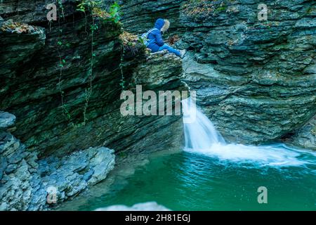 Escursionista che guarda le piccole cascate del torrente Rui, Mel, Belluno, Italia Foto Stock