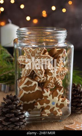 Biscotti di Natale in un vaso di vetro, coni di pino e una ghirlanda. Scatto verticale. Foto Stock