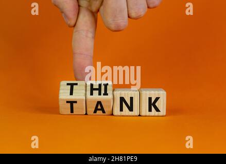 Think Tank. L'uomo d'affari trasforma i cubi di legno e cambia la parola 'serbatoio' in 'pensare' o viceversa. Bella tavola arancione, sfondo arancione, poliziotto Foto Stock