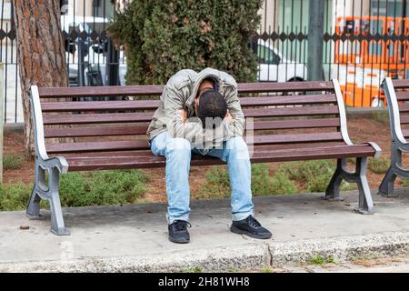 Uomo disperato seduto su una panchina pubblica Foto Stock
