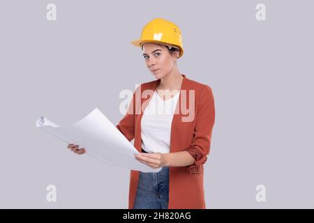 Ragazza costruzione lavoratore Holding House piano in mani guardando esso. Ragazza architetto che tiene Blueprints. Casco rigido giallo. Foto Stock