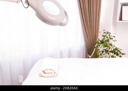 Salone di bellezza. Foto di un armadio per ringiovanire il viso con un tavolo, asciugamano bianco e una lampada, tutti sono dispositivi cosmetologici. Foto Stock