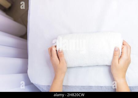 Sfondo. Vista dall'alto delle mani della donna con manicure interessante mettere l'asciugamano su un tavolo da massaggio in un salone di bellezza. Pronto per il lavoro, la bellezza Foto Stock