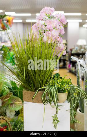 Fiori artificiali in interior design, foglie verdi, delicato fiore rosa orchidea. Fotografia verticale per il design Foto Stock