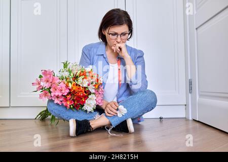 Triste turbata donna di mezza età con un bouquet di fiori Foto Stock