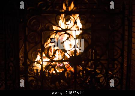 Camino fuoco dietro una griglia di protezione in ferro battuto Foto Stock