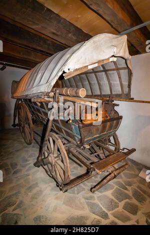 Foto posteriore di un carrello tradizionale con ruote in legno, rivestito di materiale e caricato con vari oggetti in legno Foto Stock